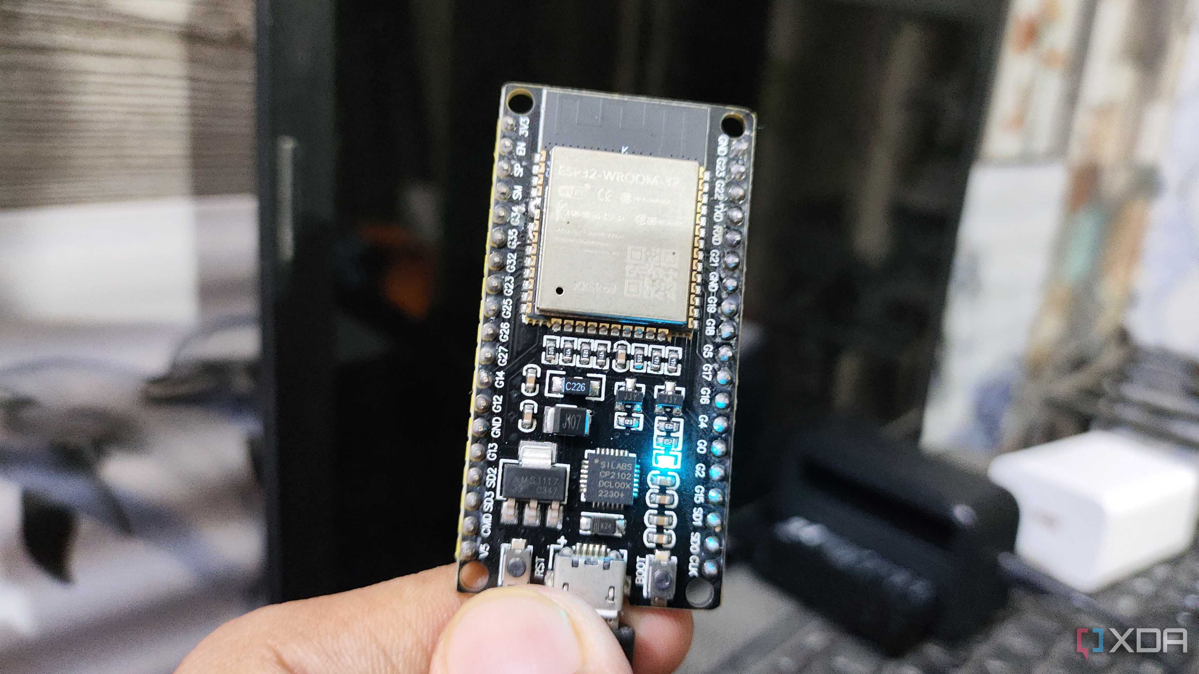 A person holding an ESP32, with an LED glowing on the microcontroller