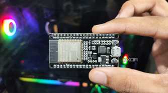 A person holding an SP32 microcontroller in front of a PC