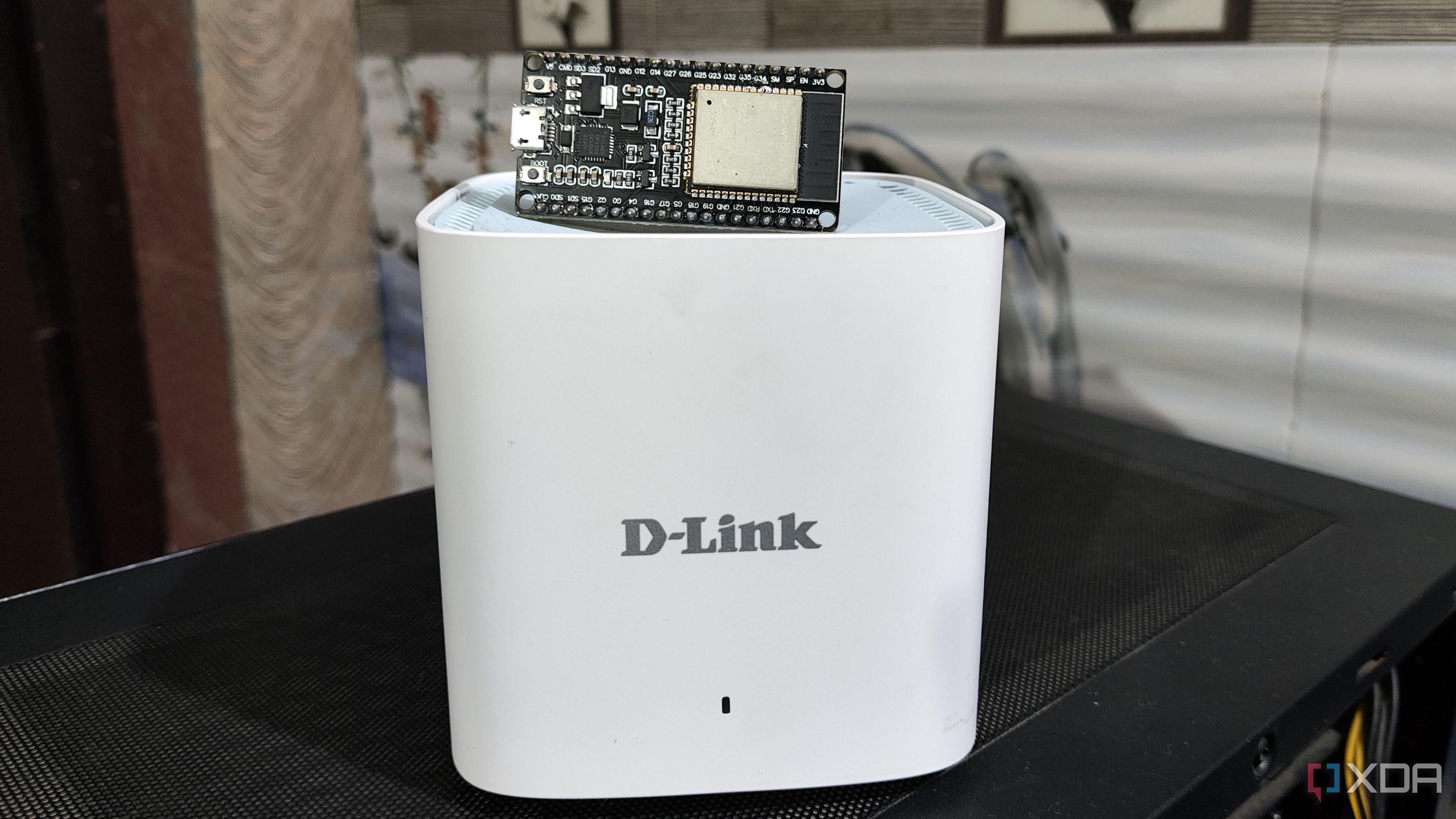 An ESP32 lying on top of a D-Link Eagle Pro mesh router