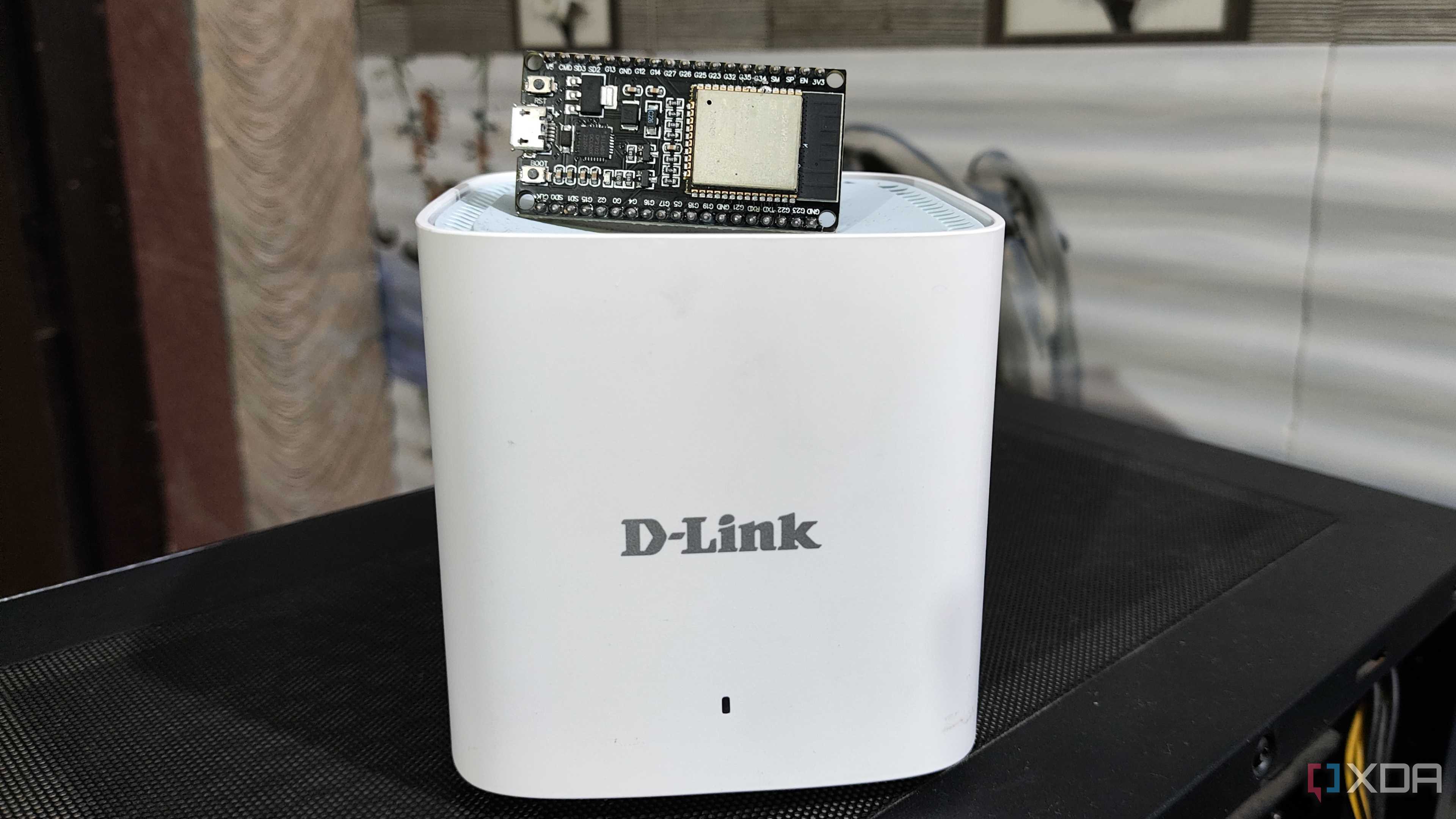 An ESP32 lying on top of a D-Link Eagle Pro mesh router