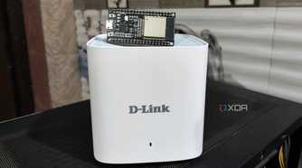 An ESP32 lying on top of a D-Link Eagle Pro mesh router