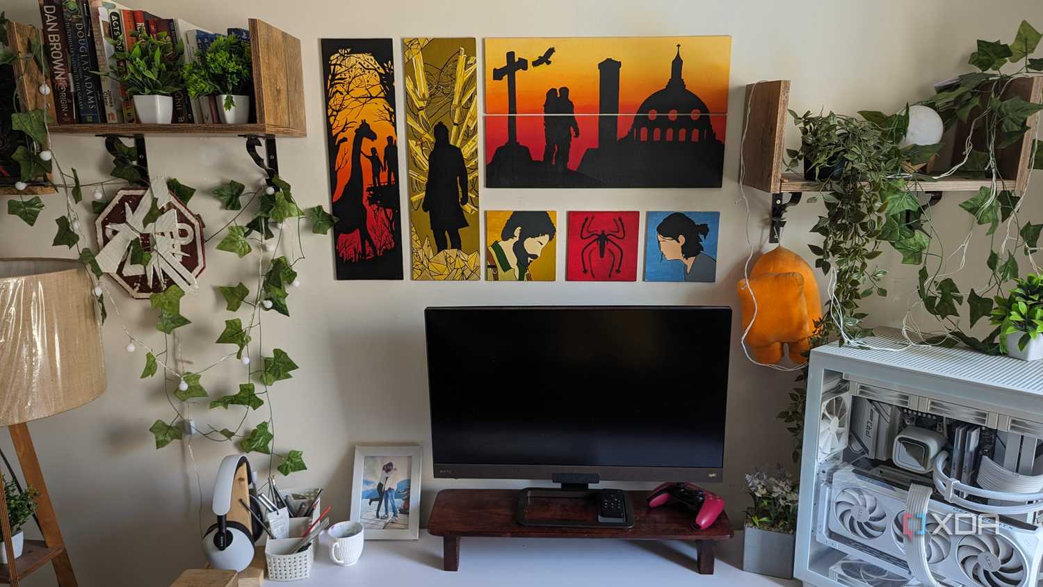 A PC setup with faux plants and leaves and paintings on the wall