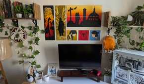A PC setup with faux plants and leaves and paintings on the wall
