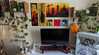 A PC setup with faux plants and leaves and paintings on the wall