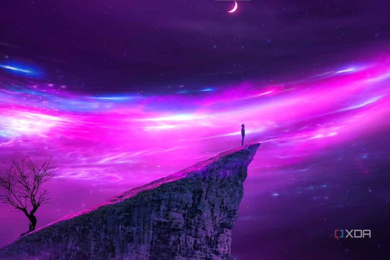 A wallpaper showing a person standing on the edge of a cliff looking at a purple universe