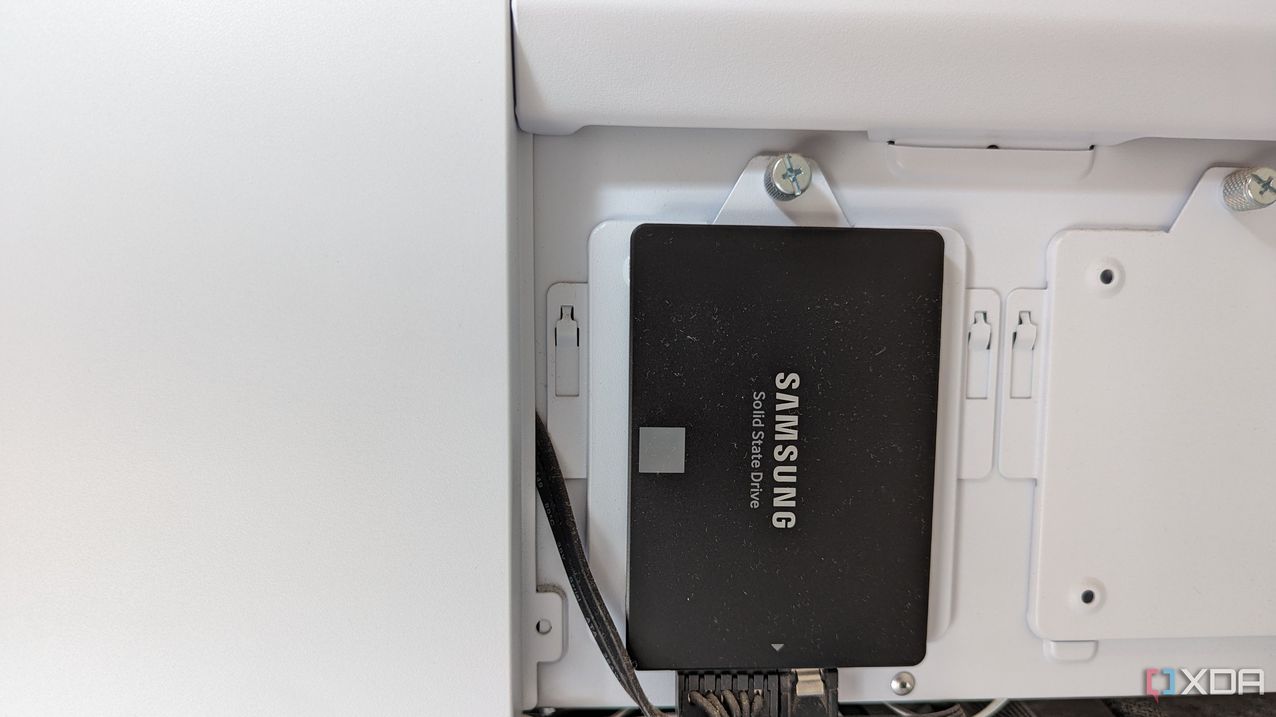 Una imagen de un SSD Samsung 860 EVO de 250 GB en negro instalado en una carcasa blanca.