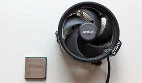 Ryzen 5 1600 CPU next to its stock cooler on a white surface