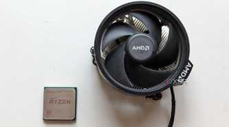 Ryzen 5 1600 CPU next to its stock cooler on a white surface