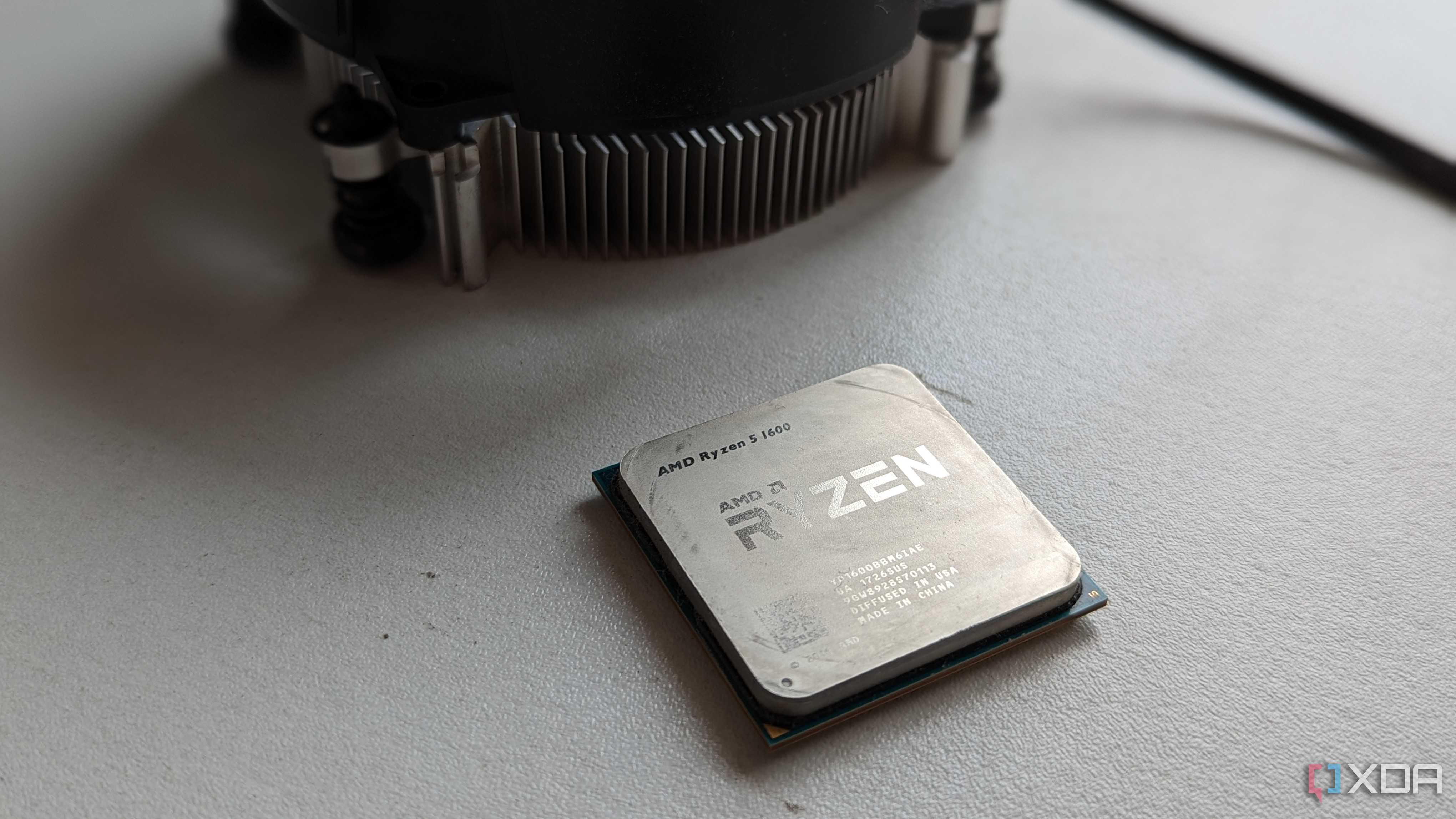 Ryzen 5 1600 processor next to stock cooler on a white surface