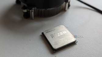 Ryzen 5 1600 processor next to stock cooler on a white surface