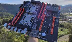 A person holding an X99 server motherboard with two Intel Xeon CPUs slotted in