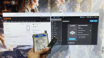 A person holding an HDD and an SSD in front of a monitor displaying the TrueNAS Scale and Unraid web UIs