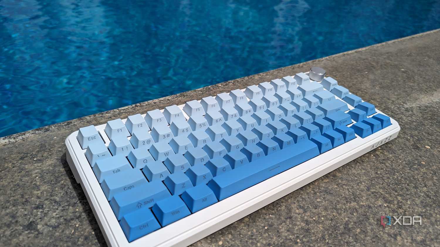 A blue-white keyboard near on a hard surface near a swimming pool