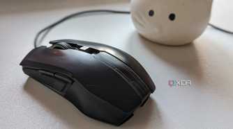 A black wired gaming mouse on a white surface next to a plant