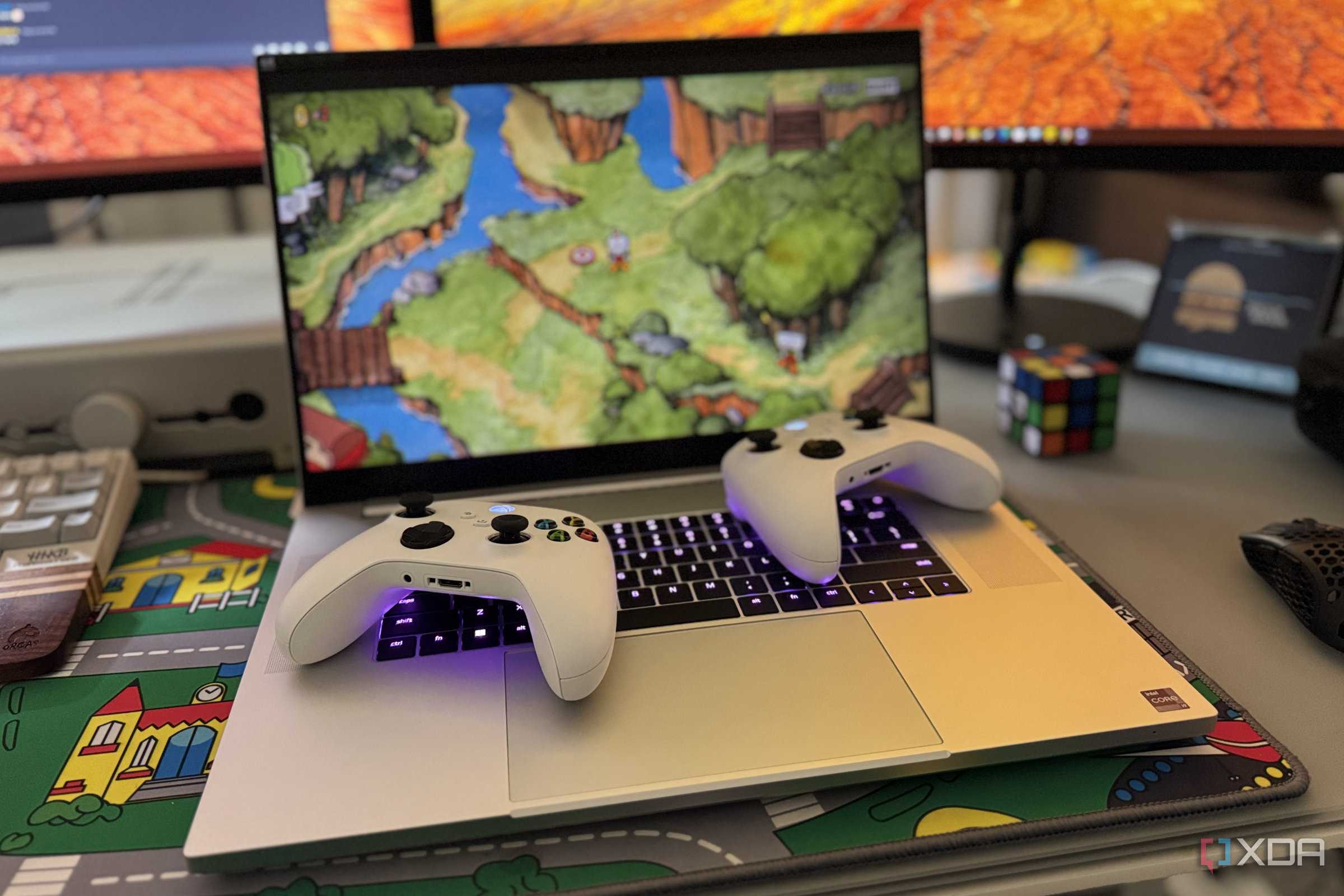 two xbox controllers laid on a razer blade 18 laptop playing cuphead