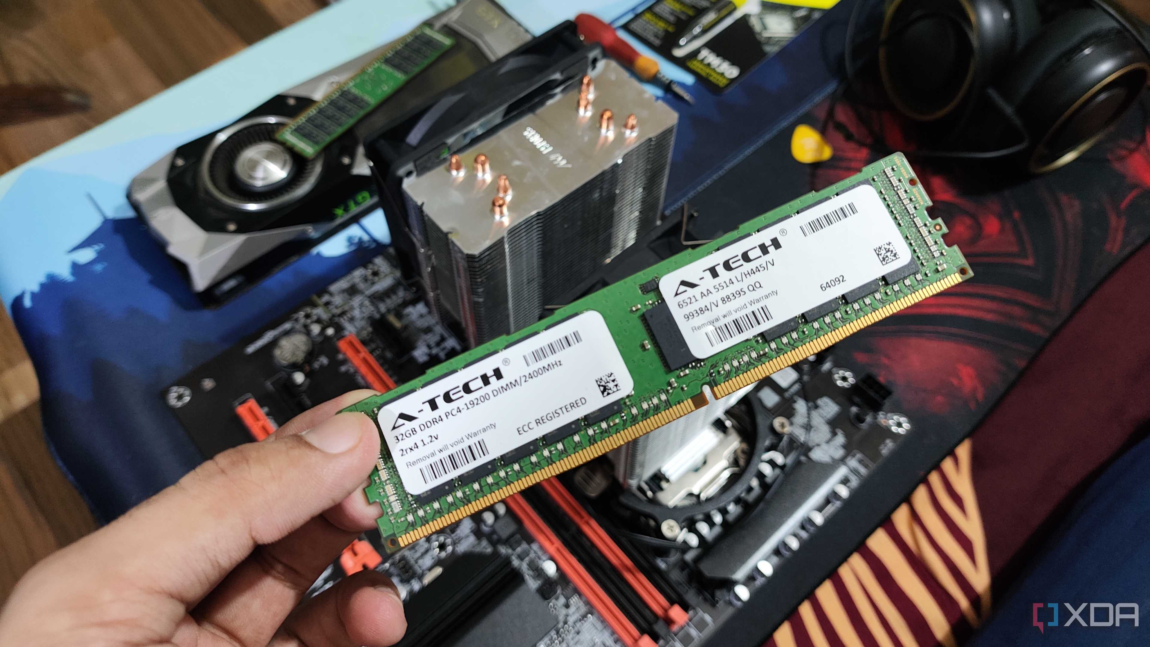 A person holding an ECC memory module, with a server PC, headphones, and a GTX 1080 in the background