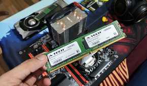 A person holding an ECC memory module, with a server PC, headphones, and a GTX 1080 in the background