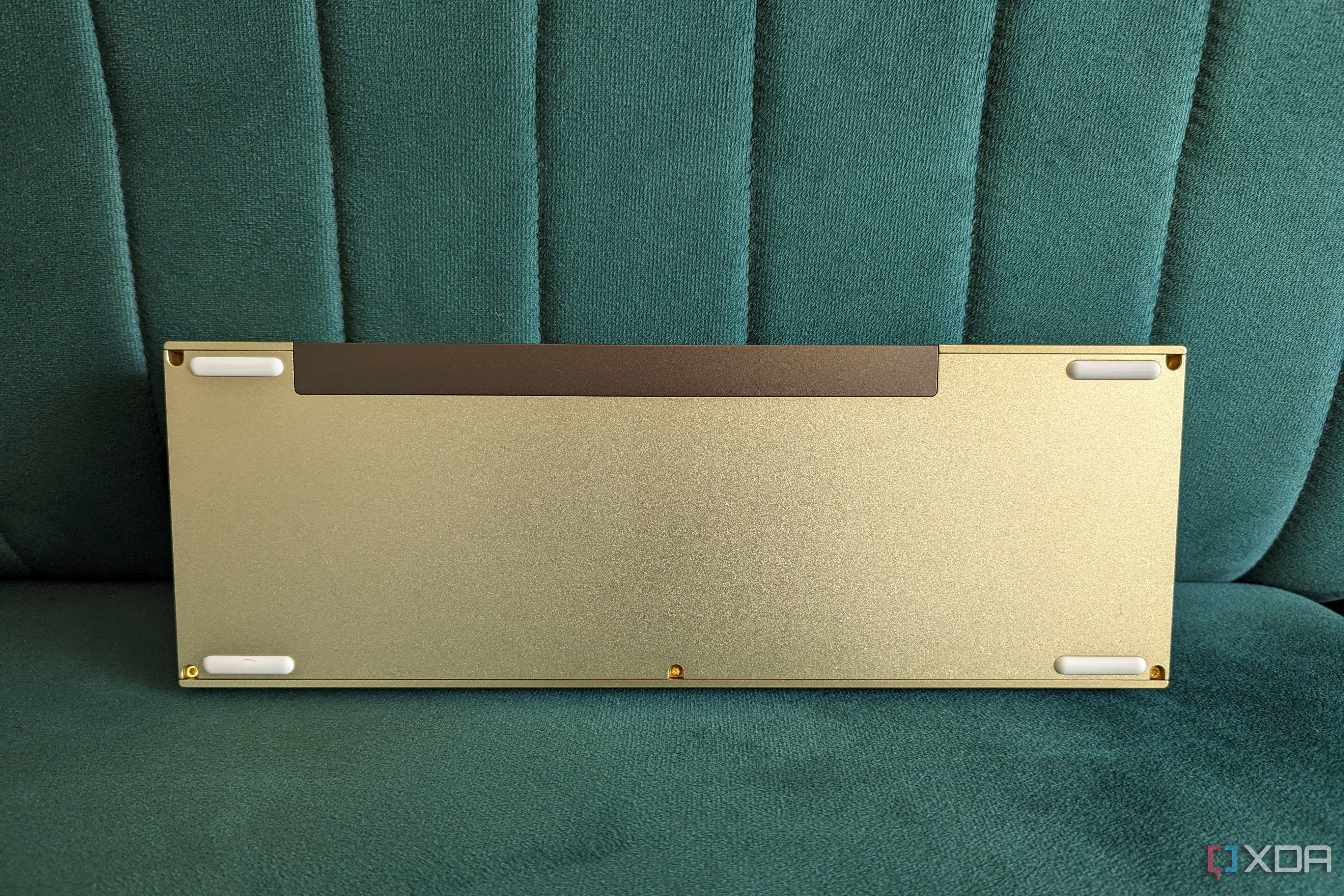 Bottom view of a gold and white mechanical keyboard on a green surface