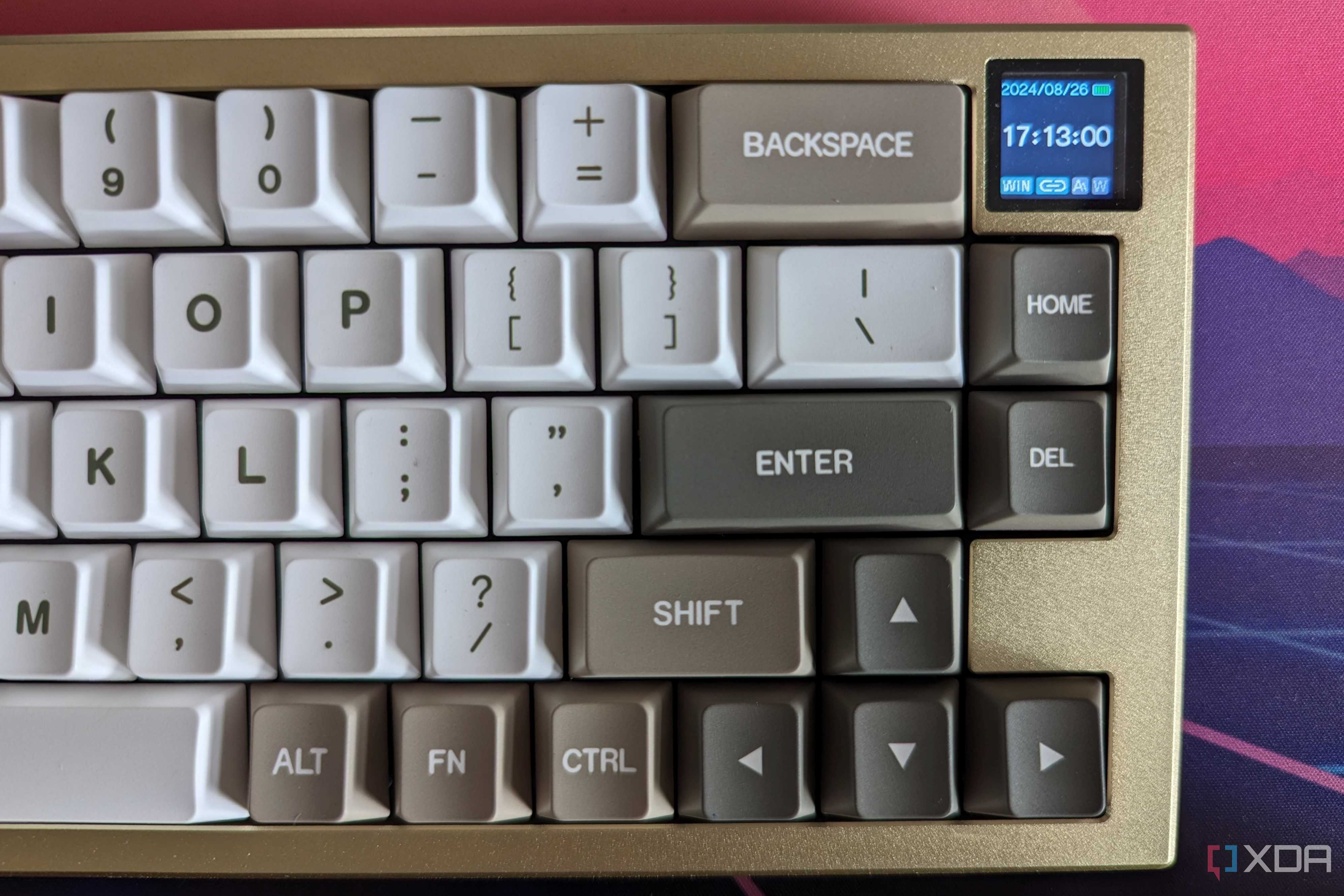 A gold and white mechanical keyboard showing a date and time on its LCD screen