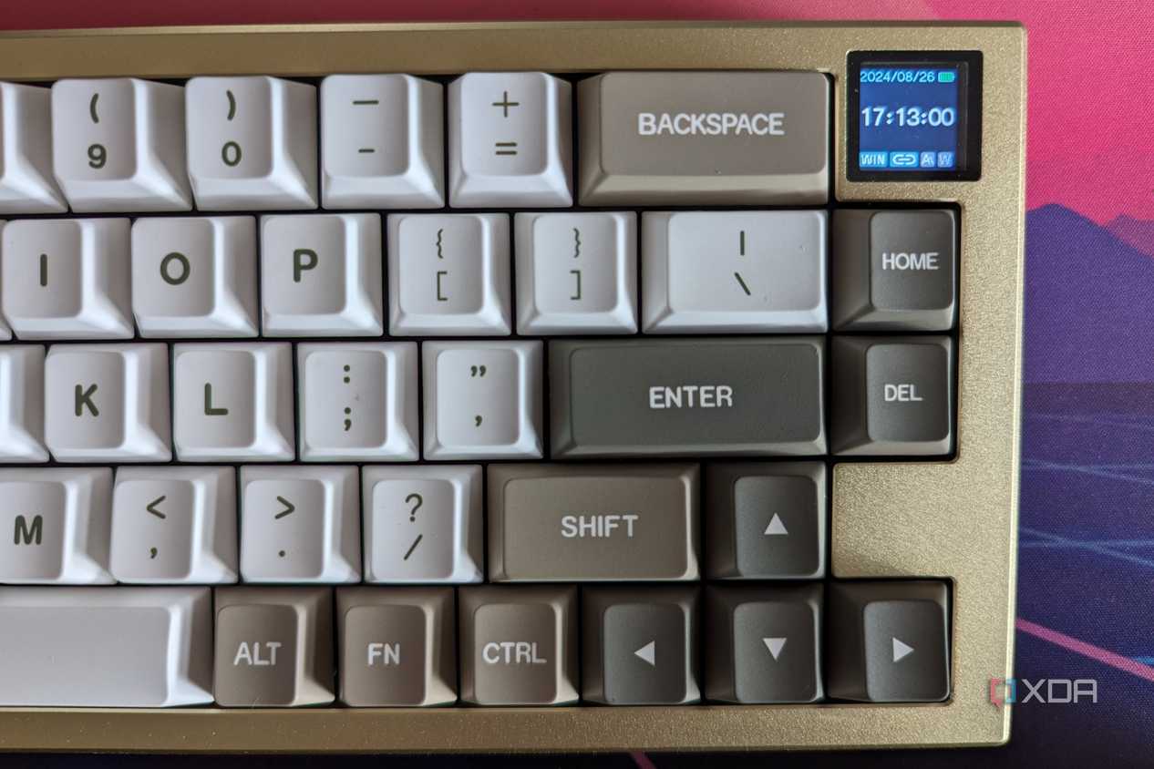 A gold and white mechanical keyboard showing a date and time on its LCD screen