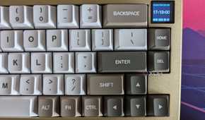 A gold and white mechanical keyboard showing a date and time on its LCD screen