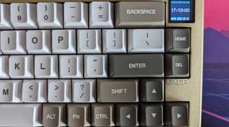 A gold and white mechanical keyboard showing a date and time on its LCD screen