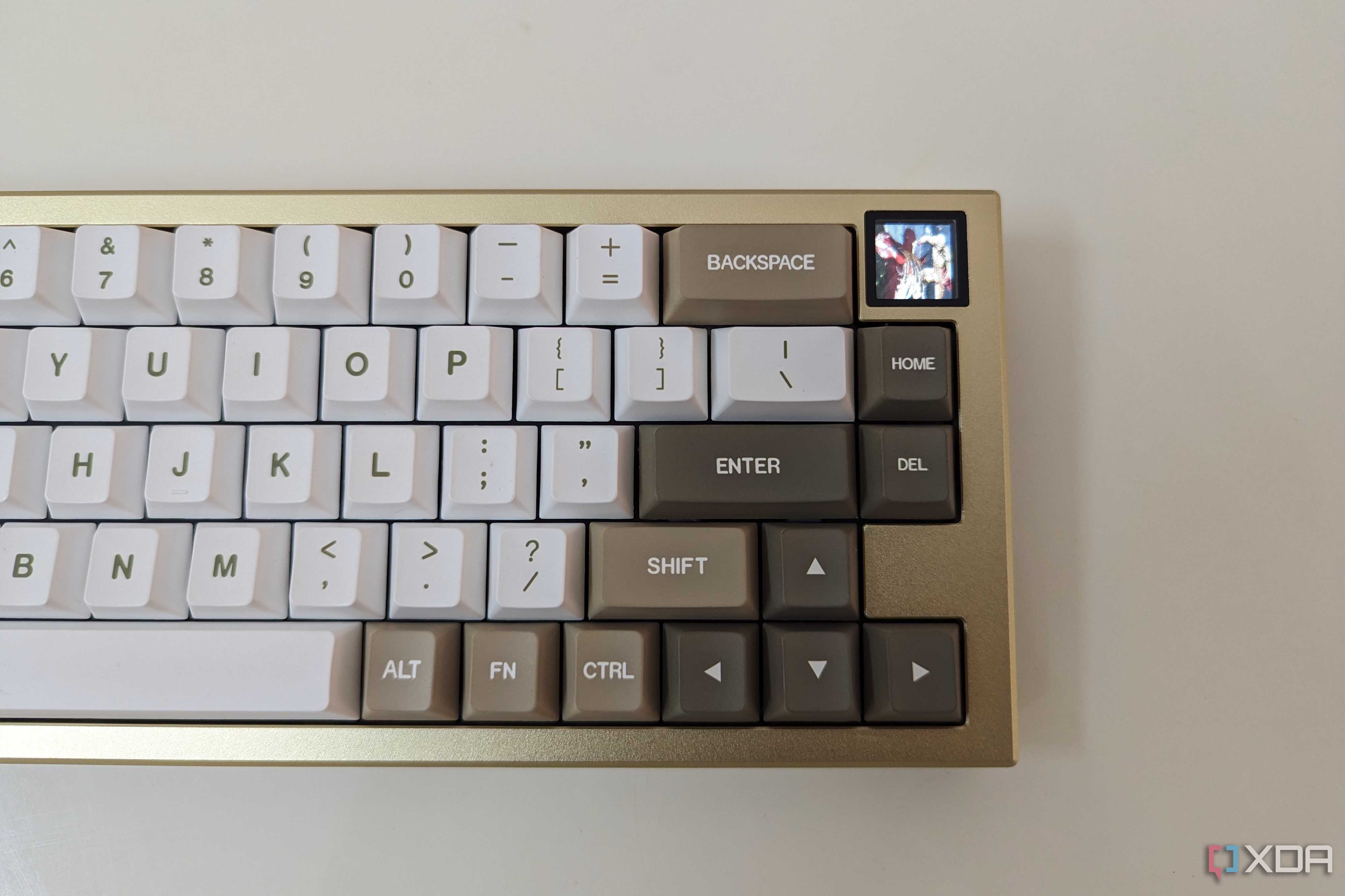 A gold and white mechanical keyboard showing a GIF on its LCS screen