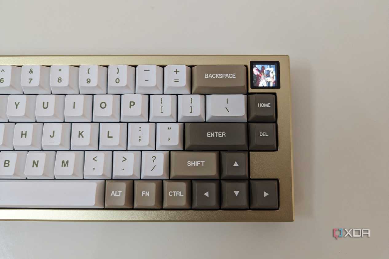 A gold and white mechanical keyboard showing a GIF on its LCS screen