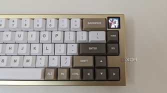 A gold and white mechanical keyboard showing a GIF on its LCS screen