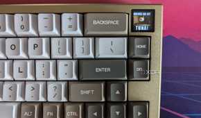 A gold and white mechanical keyboard showing a GIF on its LCD screen