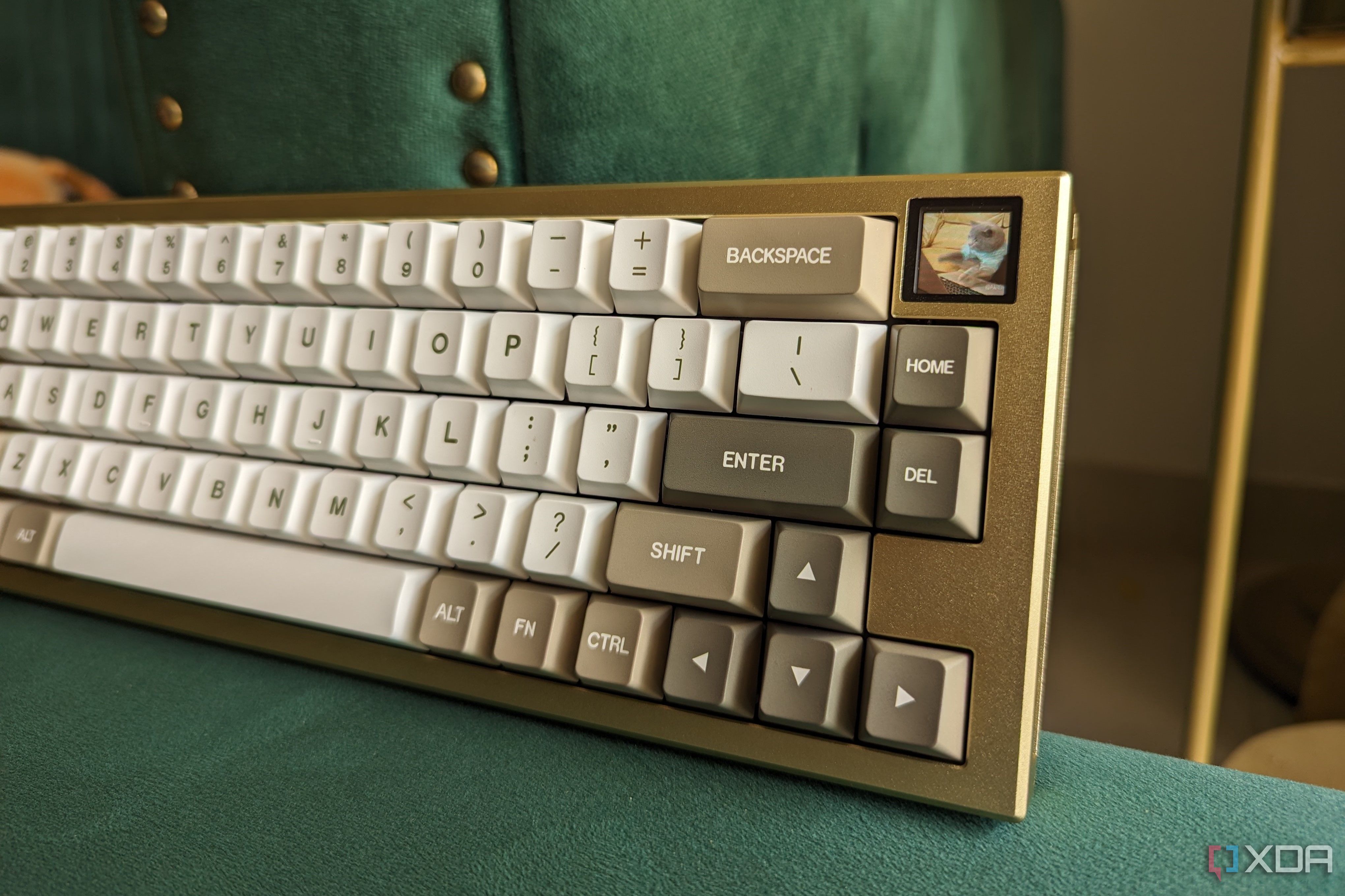A gold and white mechanical keyboard showing a cat GIF on its LCD screen