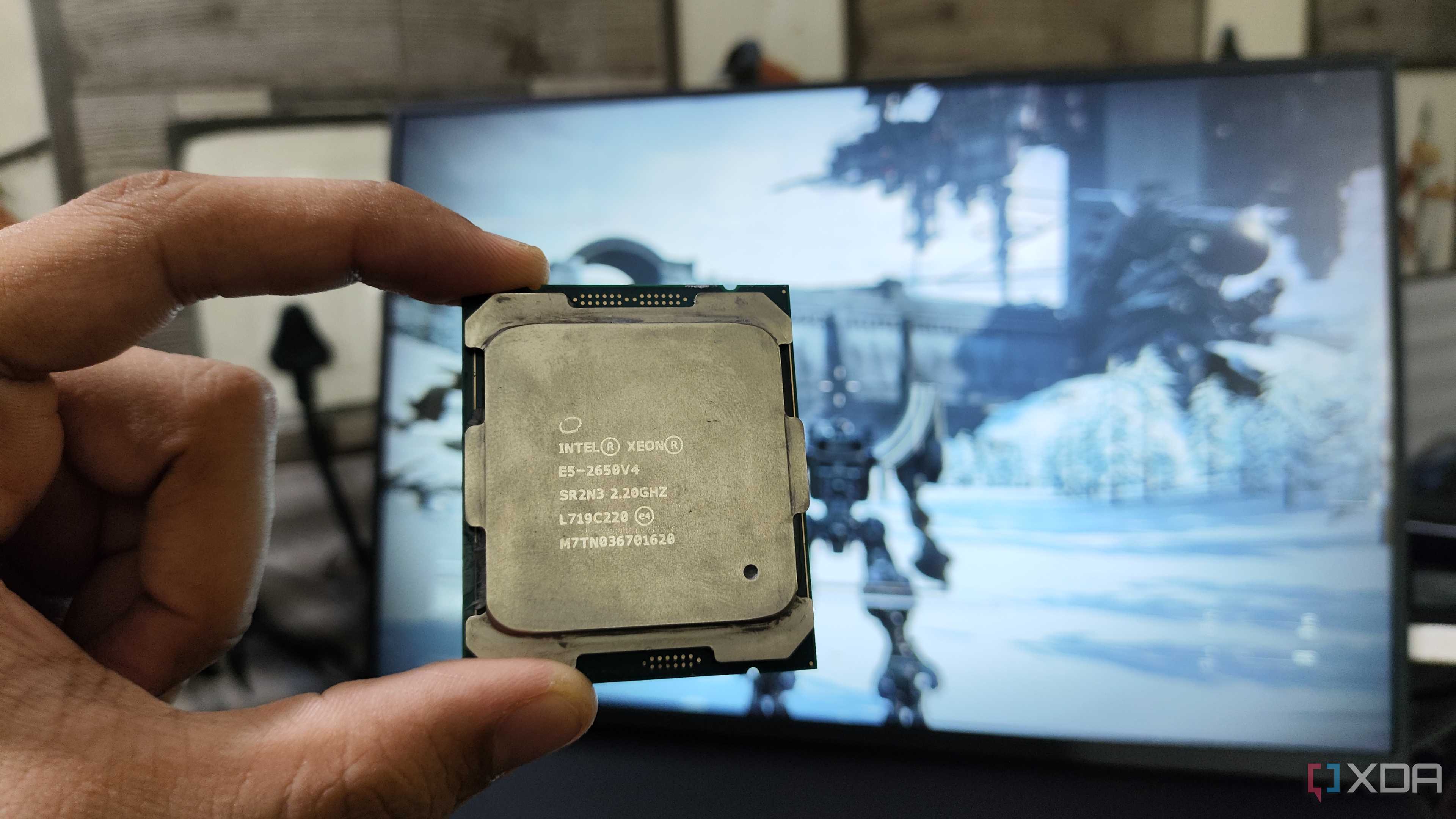 A person holding a server-grade Intel Xeon E5-2650 v4 processor in front of a monitor