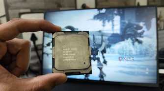 A person holding a server-grade Intel Xeon E5-2650 v4 processor in front of a monitor