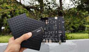 A person holding two external HDDs and an SSD in front of the Milk-V Jupiter