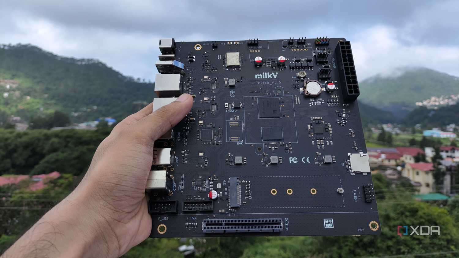 A personal holding the K1 version of the Milk-V Jupiter mini-ITX motherboard