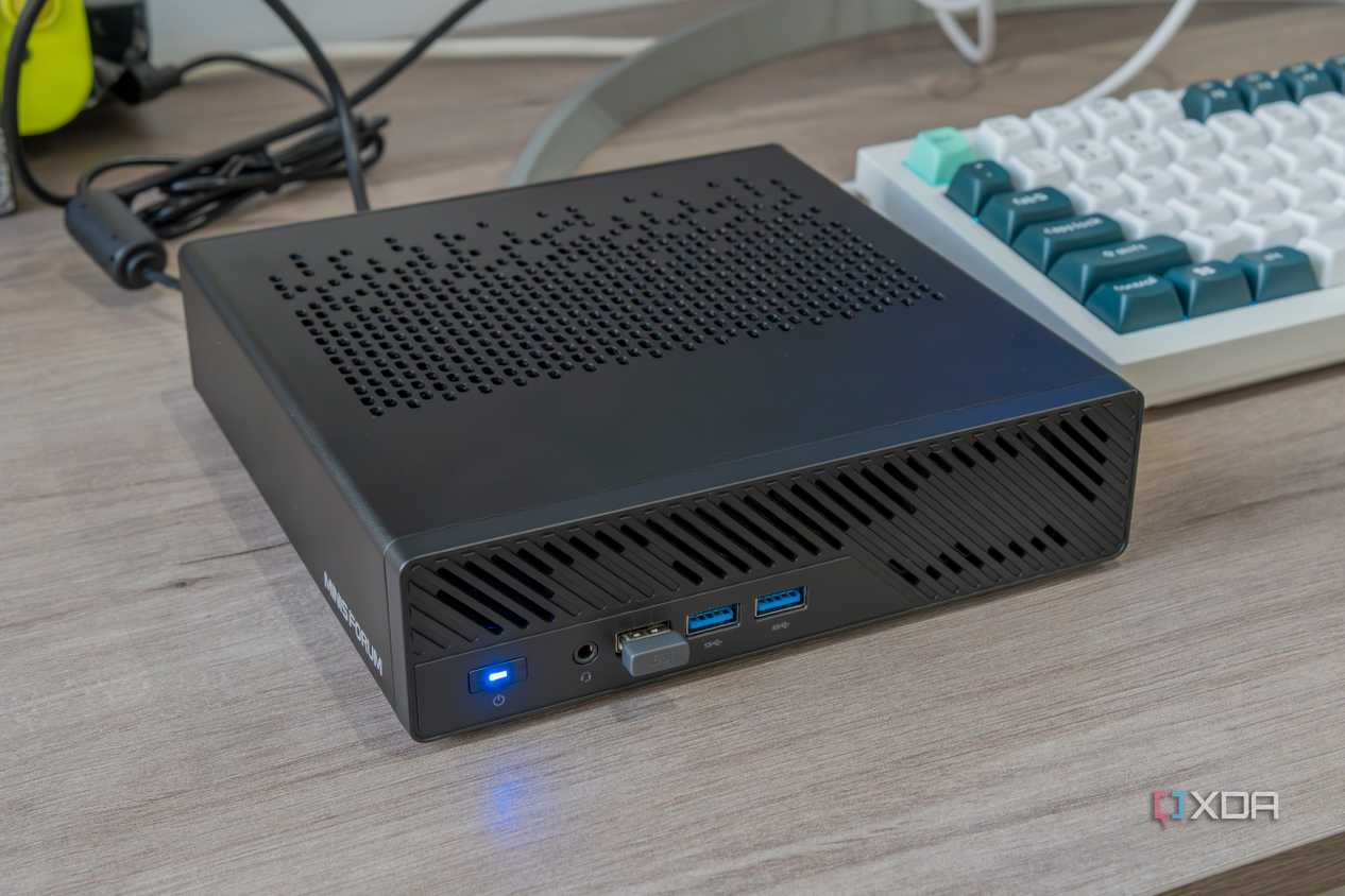 Angled view of the Minisforum MS-A1 powered on next to a keyboard and other peripherals