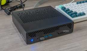 Angled view of the Minisforum MS-A1 powered on next to a keyboard and other peripherals