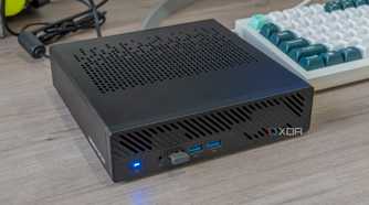 Angled view of the Minisforum MS-A1 powered on next to a keyboard and other peripherals