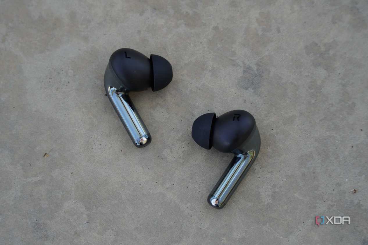 The OnePlus Buds Pro 3 earbuds on a concrete bench.