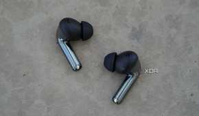 The OnePlus Buds Pro 3 earbuds on a concrete bench.