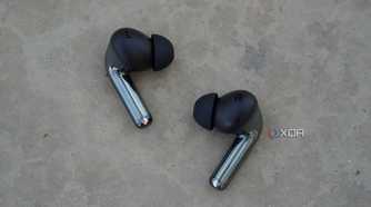 The OnePlus Buds Pro 3 earbuds on a concrete bench.