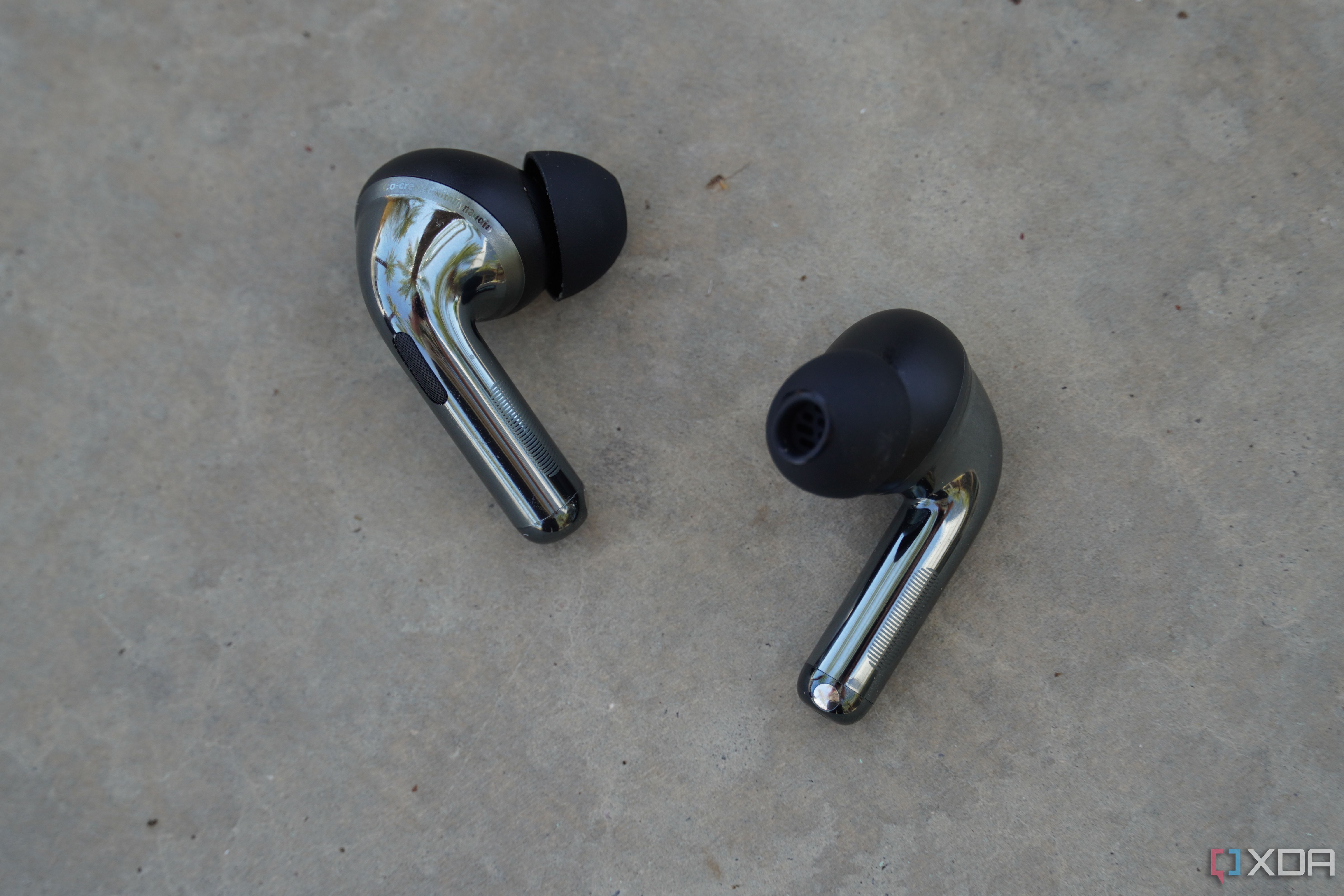 The OnePlus Buds Pro 3 earbuds on a concrete bench.