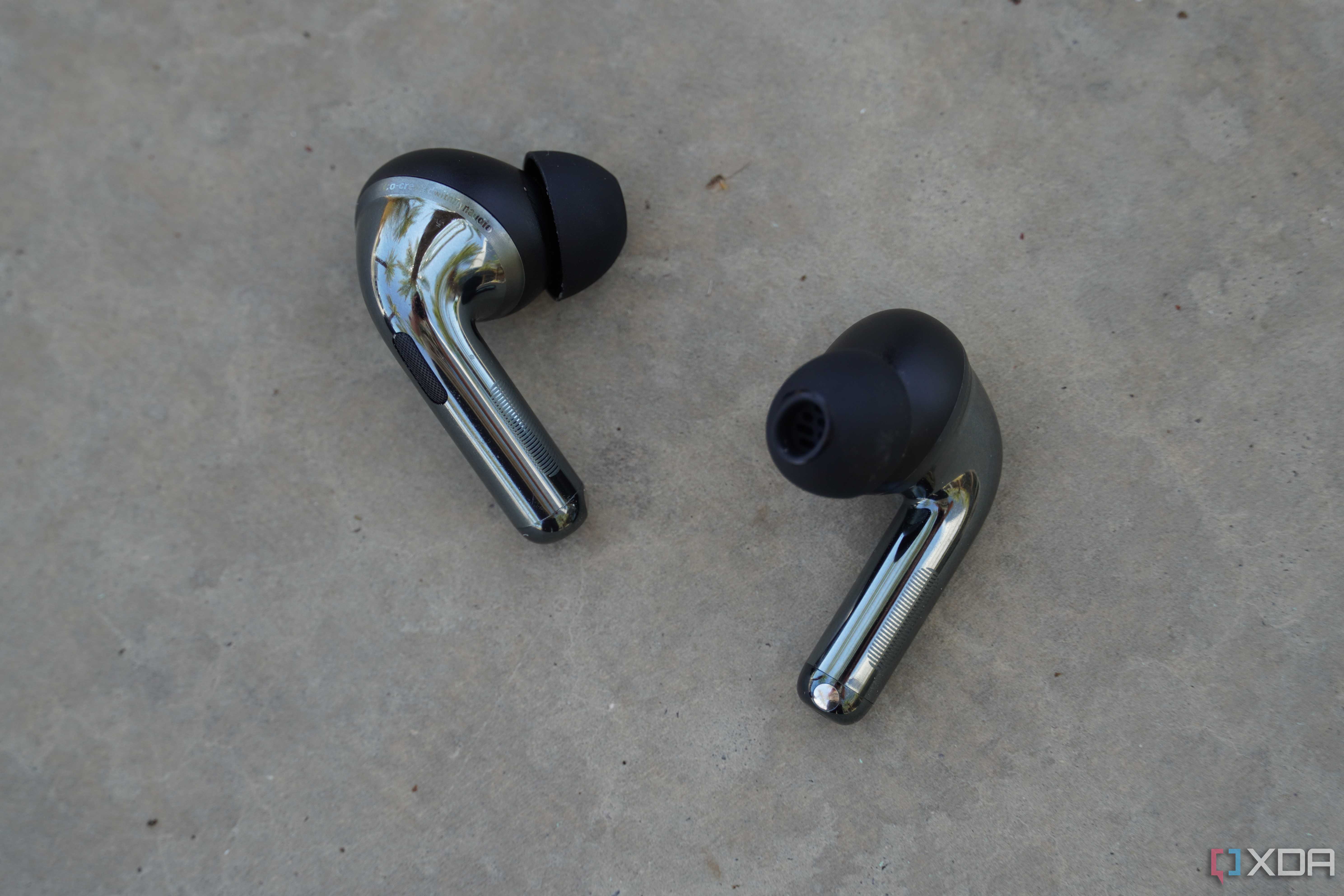 The OnePlus Buds Pro 3 earbuds on a concrete bench.