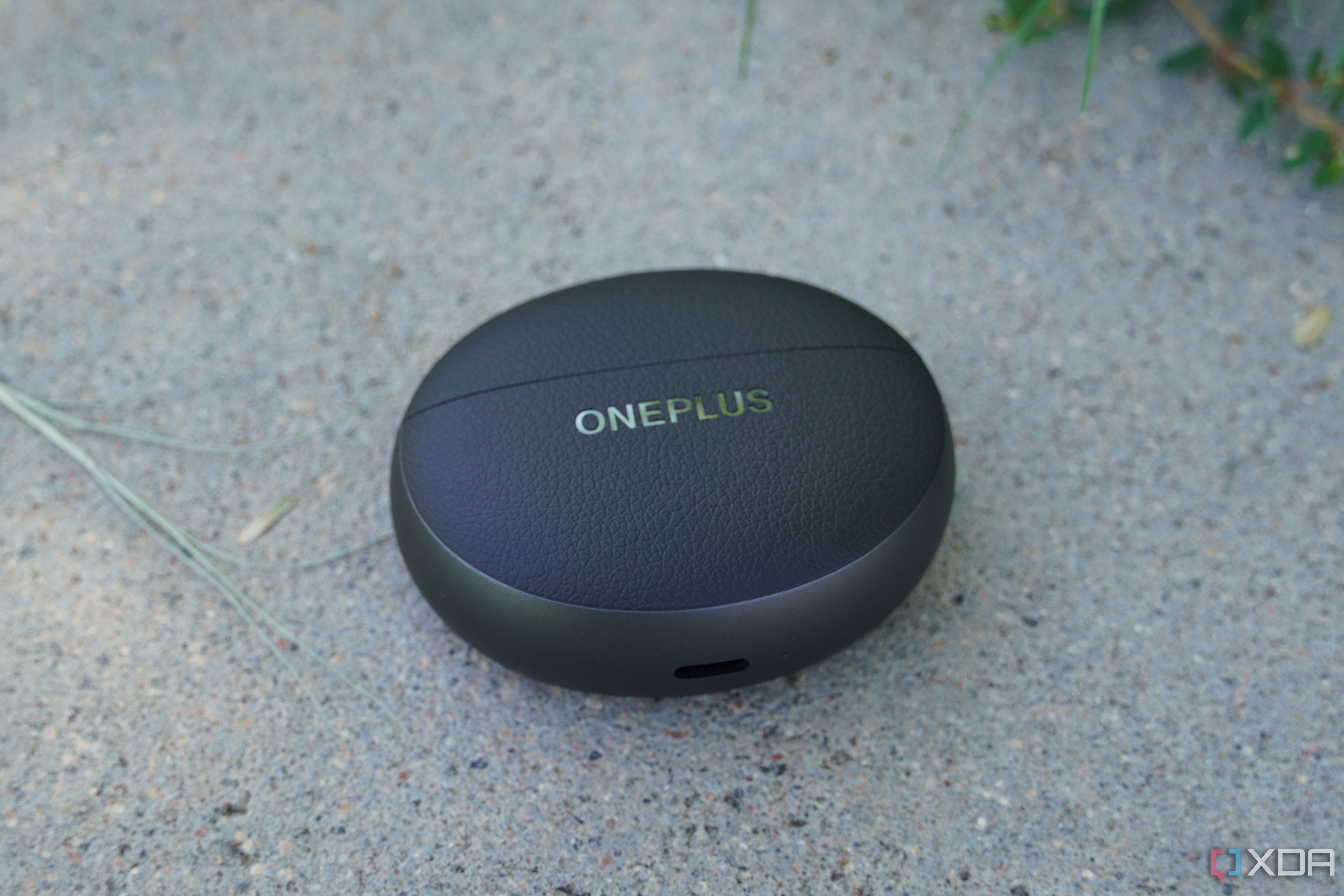 The OnePlus Buds Pro 3 case on a concrete bench.