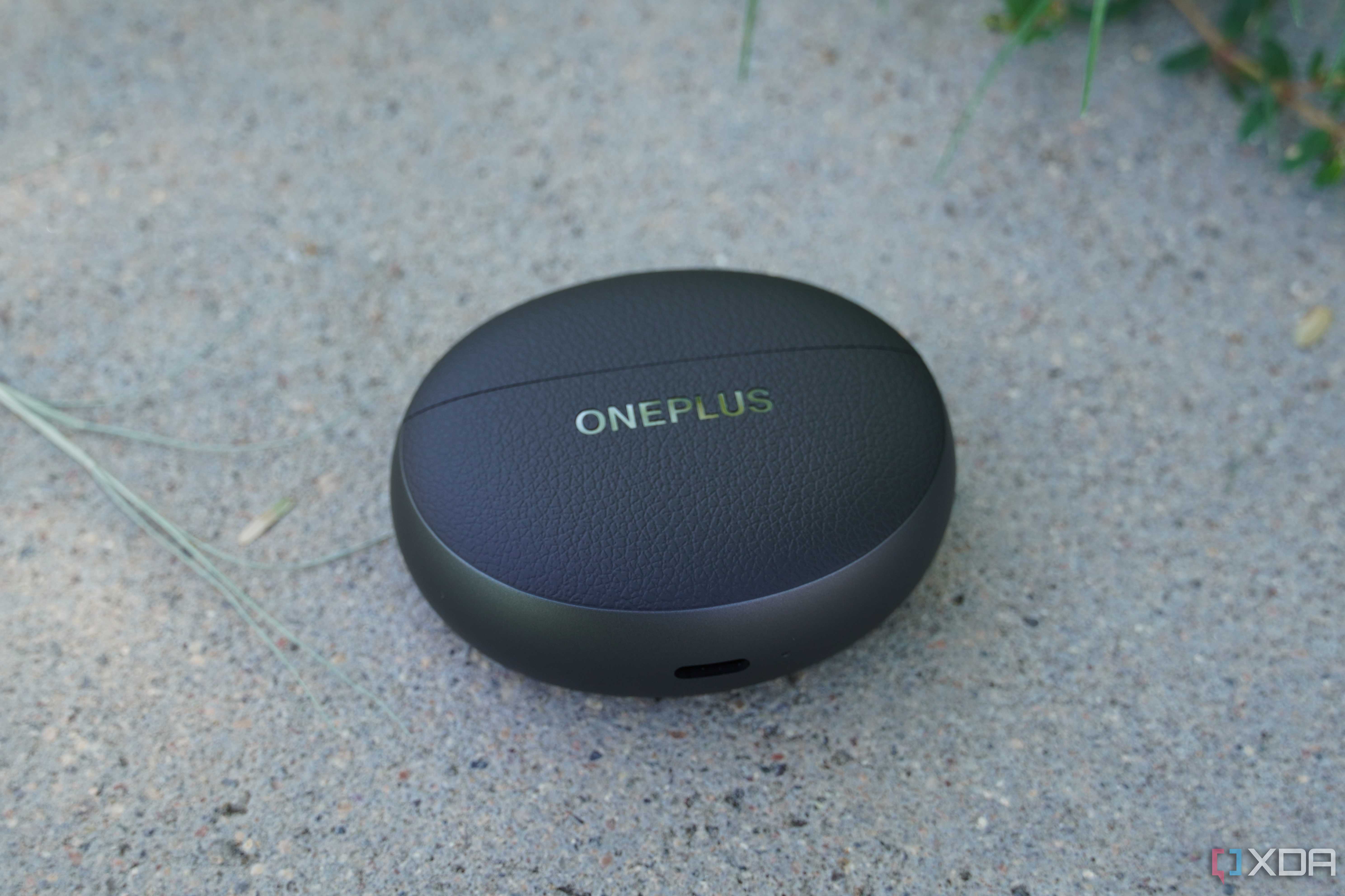 The OnePlus Buds Pro 3 case on a concrete bench.