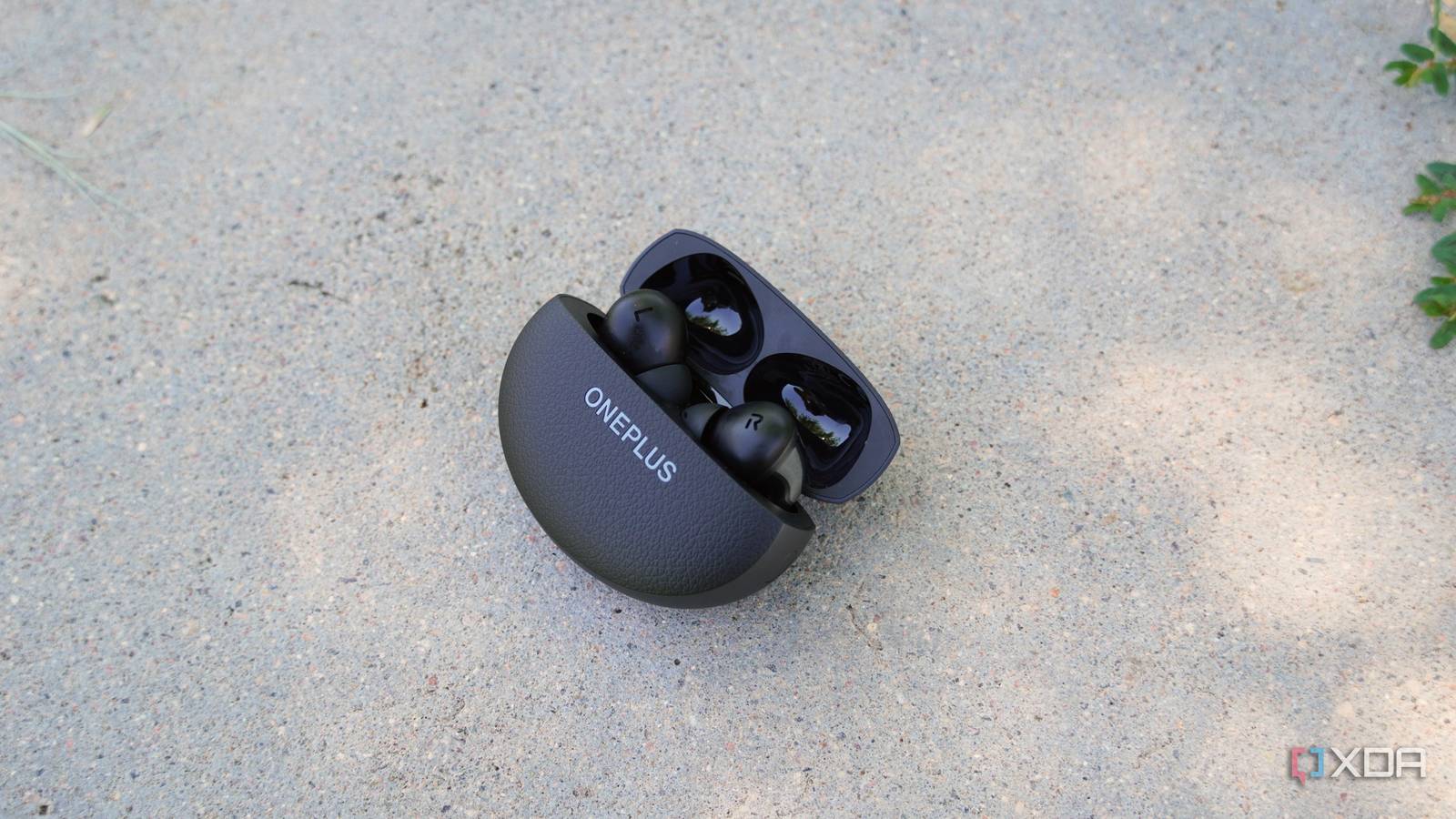 The OnePlus Buds Pro 3 opened on a concrete bench.