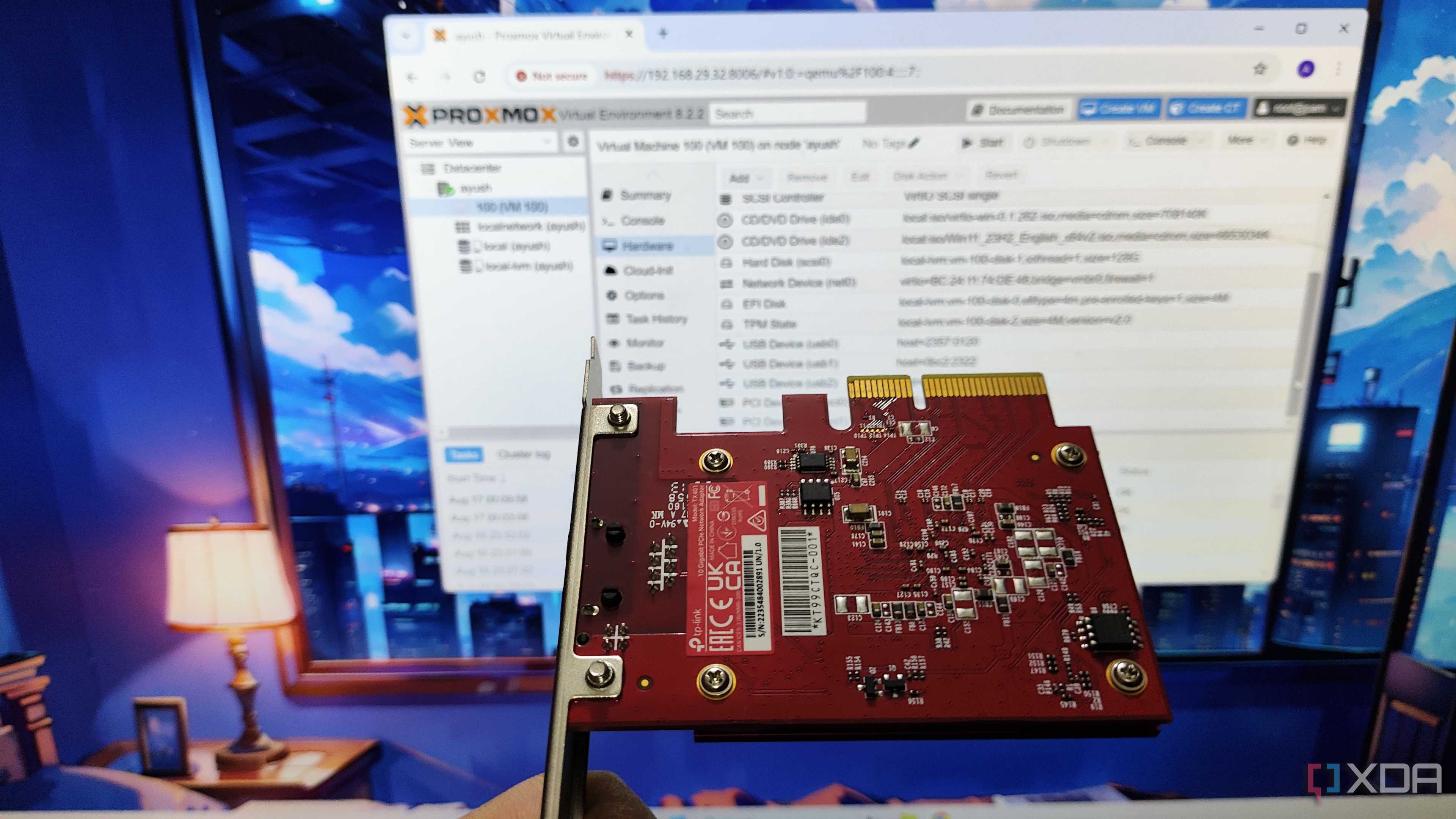 An Ethernet card held in front of a monitor running Proxmox