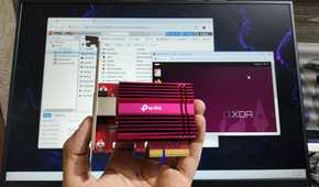 A person holding a 10GbE NIC in front of a monitor displaying the Proxmox UI
