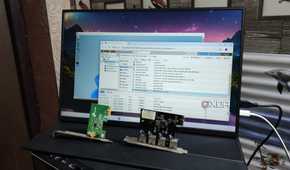 A WLAN card and a USB expansion card kept in front of a monitor displaying the Proxmox UI