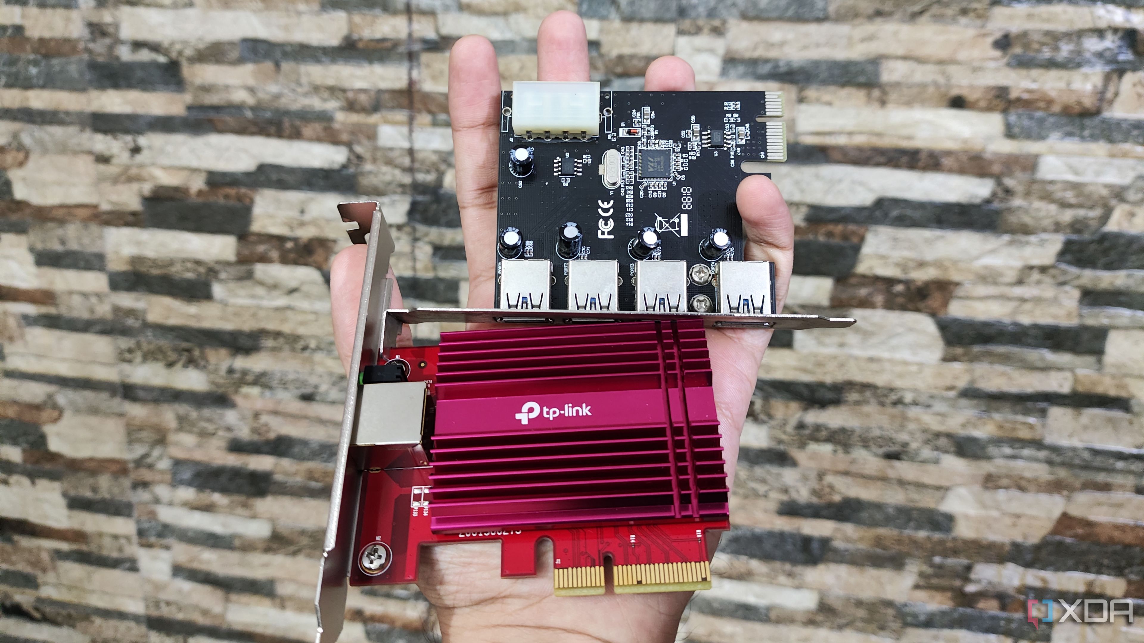A person holding an NIC and a PCIe-to-USB card